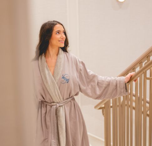 a woman walking up the stairs in a plush robe