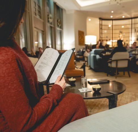 a woman in a red dress reading off a menu in a lively lounge area