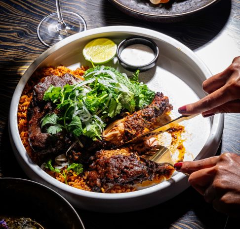 a person cutting into a chicken and rice dish
