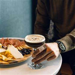 Hand holding a cocktail and charcuterie board
