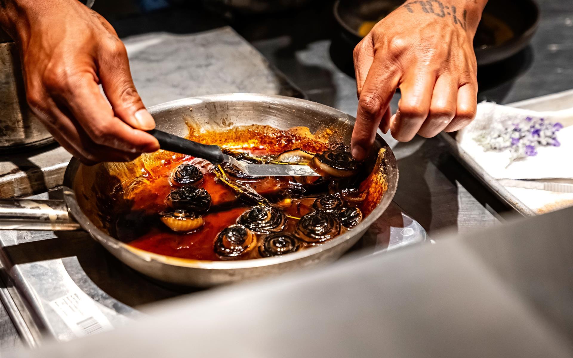 A chef holding skewers over a plate of food